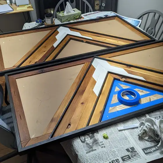 Framed panels of the geometric wood art stacked on a table part way through the build